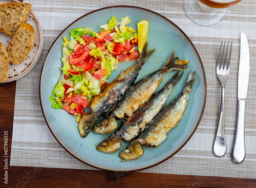 Crunchy grilled sardines garnished with fresh vegetable salad, typical dish of Portuguese cuisine
