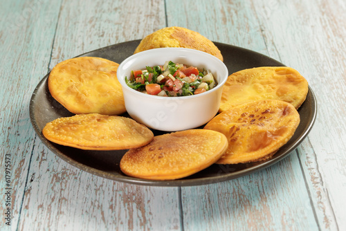 Quadro em tela Sopaipillas of pumpkin or squash in round plate on wooden table and bowl with pebre in the center