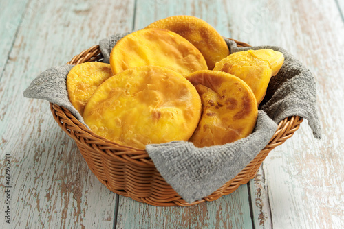Sopaipillas of pumpkin or squash in round basket with gray cloth, on wooden table in the center. typical Chilean food concept photo