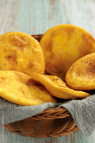 Sopaipillas of pumpkin or squash in a round basket with gray cloth, on a wooden table, vertically, with copy space. Typical Chilean food concept photo