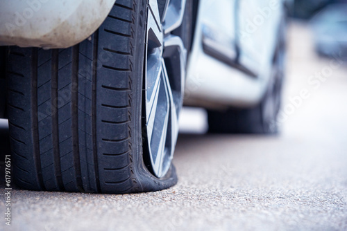 Rear right flat tire of car close-up. Insured event machine accident, tire puncture. Vehicle stands on the road with perforated rubber on a wheel with a metal disc. ServiceMobile tire fitting.