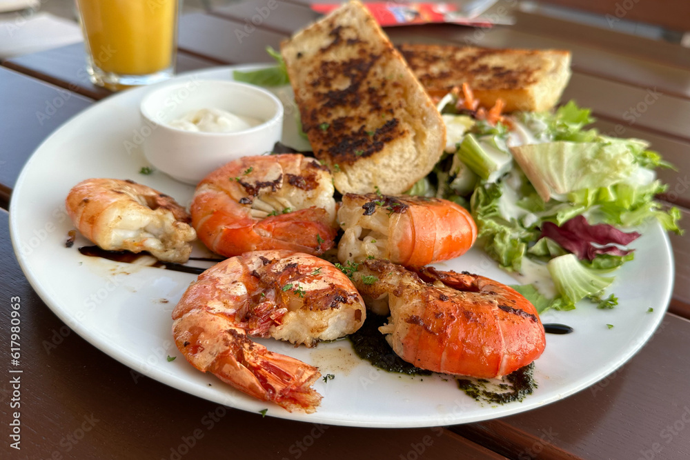 Grilled tiger prawns served with garlic breads and salad in white plate Grilled tiger prawns served with garlic breads and salad in white plate