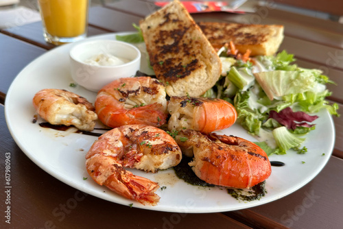 Grilled tiger prawns served with garlic breads and salad in white plate