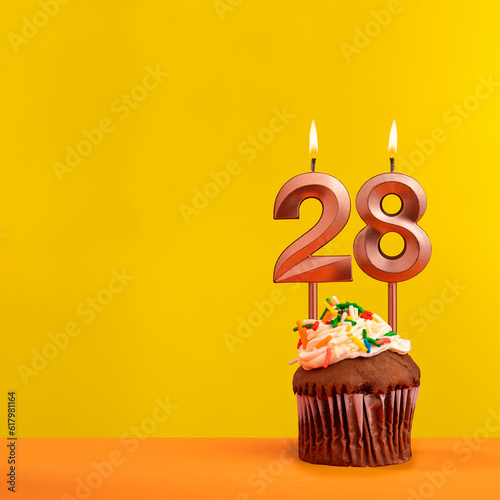 Candle with flame number 28 - Birthday card on yellow background
