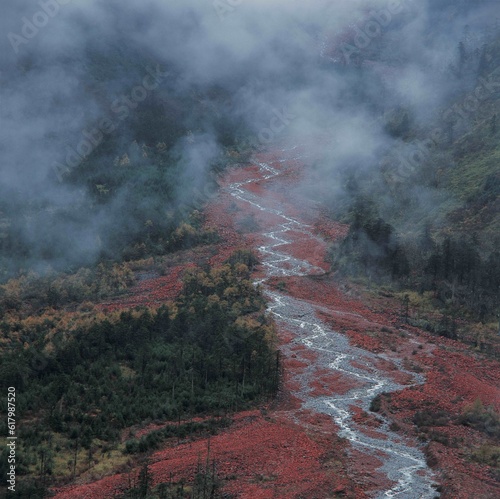 Winding stream in high elevation mountain surrounded by mist and clouds