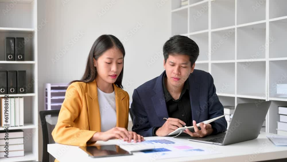 Two business workers talking on the smartphone and using laptop at the office.. Two business workers talking on the smartphone and using laptop at the office..