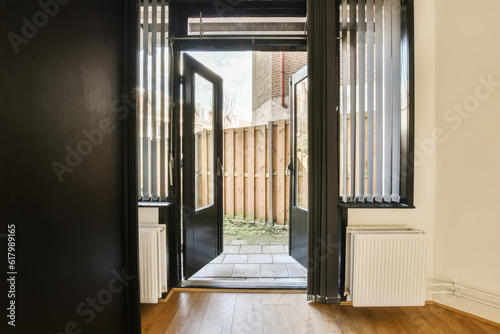 an empty room with wooden floors and black doors that lead into the entrance to the yard  where there is no one in sight