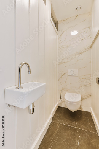 a white bathroom with marble flooring and wall to wall tile in the shower stall  which is also used as a toilet