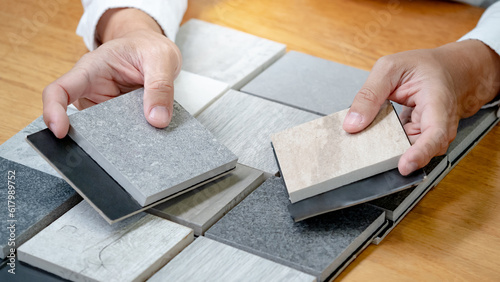 Stampa su tela Architect hand choosing sample of stone material or tile texture collection on the table in studio