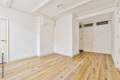 an empty room with white walls and wood flooring on the right, there is a door to the left
