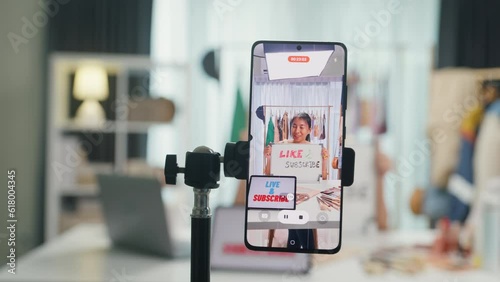 Close-up phone screen recording Asia lady vlogger looking at phone camera live stream  hold whiteboard talk follower introduce her chanel ask audience like subscribe share her chanel at house studio.