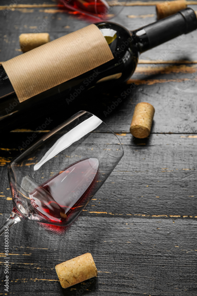 Bottle and glass of red wine on dark wooden background