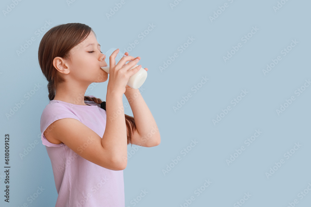 Little girl drinking milk on light blue background Little girl drinking milk on light blue background