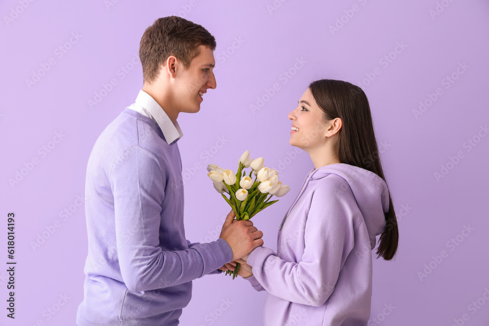 Happy young couple with tulips on lilac background Happy young couple with tulips on lilac background