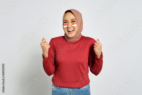 Excited young Asian women celebrate Indonesian independence day on 17 August, standing with raised hands isolated over white background photo