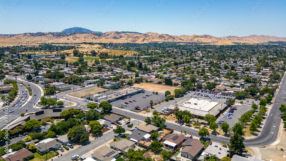 Drone photo over a neighborhood in Antioch, California with houses, commercial buildings and a blue sky with room for text