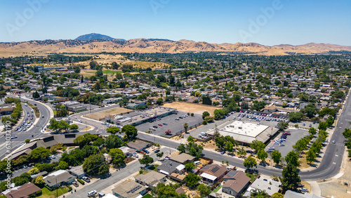 Drone photo over a neighborhood in Antioch, California with houses, commercial buildings and a blue sky with room for text