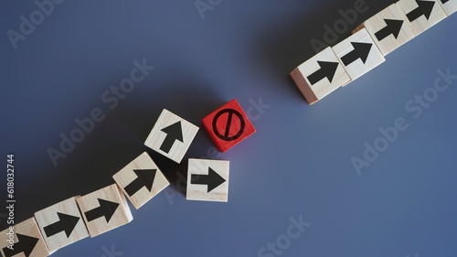 Wooden blocks with arrow and stop icon. Delays and disruptions, stop the process, critical error concept photo