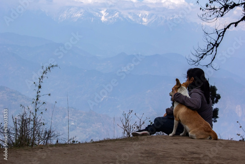 a female model sitting with a dog wearing purple jacket enjoying nature. Selective focus. Concept of friendship between human and animal. photo