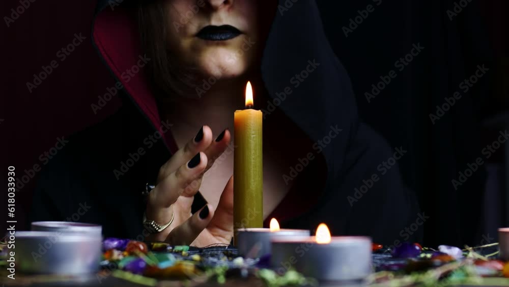 Witch hands performing a magic ritual holding a candle on a magical altar. Sorcerer rite of witchcraft and occultism. Halloween occult, esoteric and divination concept. Witch hands performing a magic ritual holding a candle on a magical altar. Sorcerer rite of witchcraft and occultism. Halloween occult, esoteric and divination concept.