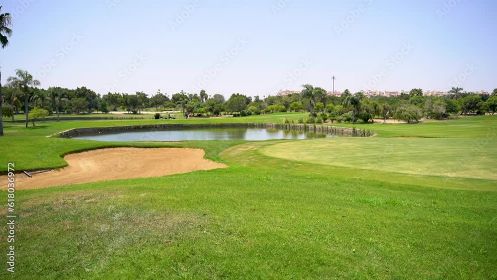 A beautiful golf course with green grass, trees, lake and feather grass on a sunny day. A beautiful golf course with green grass, trees, lake and feather grass on a sunny day.