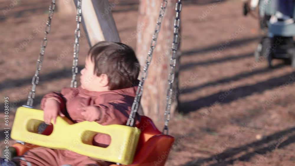 Cute baby swings on a swing towards the sun in the park Cute baby swings on a swing towards the sun in the park