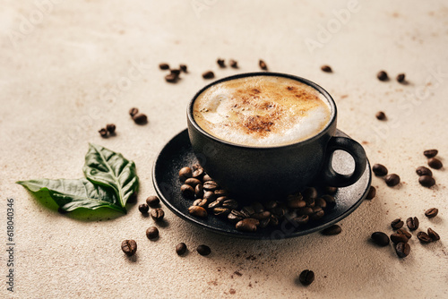 Cup of cappuccino, green coffee leaves and beans on light background. Close up