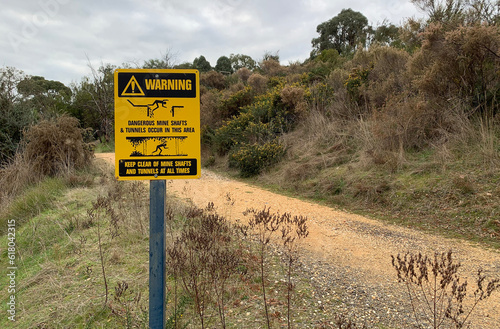 black and yellow Warning: Dangerous Mine Shafts and Tunnels Occur in this Area - Keep Clear At All Times metal sign on post near walking track