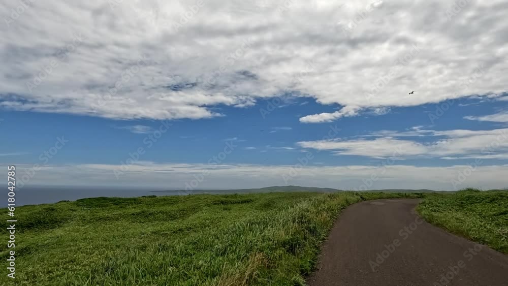 Biking along single lane island road on sunny day. Biker POV. Panorama view of coastline and sea Biking along single lane island road on sunny day. Biker POV. Panorama view of coastline and sea