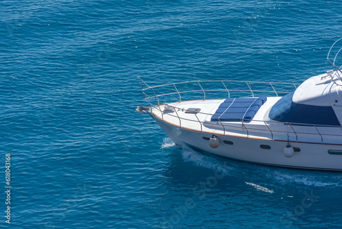 Prow of a yacht with sun loungers at the stern floating on the water surface in summer. © aapsky