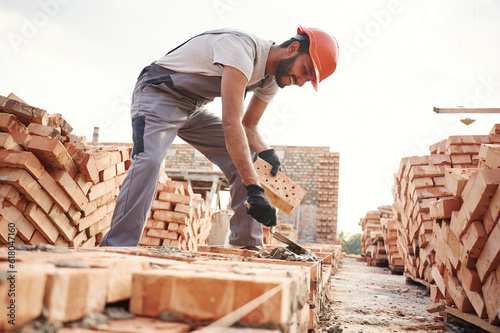 Side view, working and placing the bricks. Handsome Indian man is on the construction site