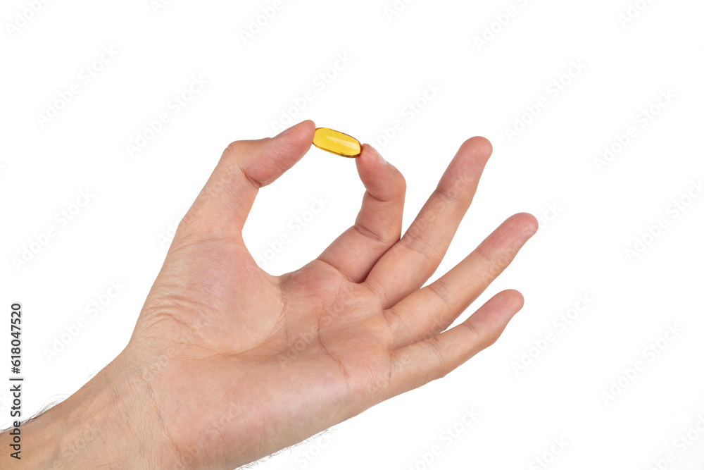 Man's hand holding a yellow pill of omega 3 isolated on a white background. Man's hand holding a yellow pill of omega 3 isolated on a white background.