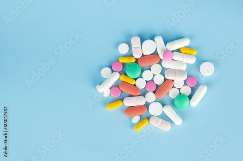 Pills and capsules on blue background. Top view with copy space