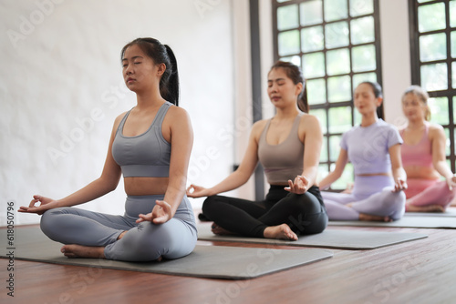 Groups of Asian women practicing basic position relaxing meditation on the mat floor at yoga class fitness gym. Women asian exercising in fitness studio yoga classes.