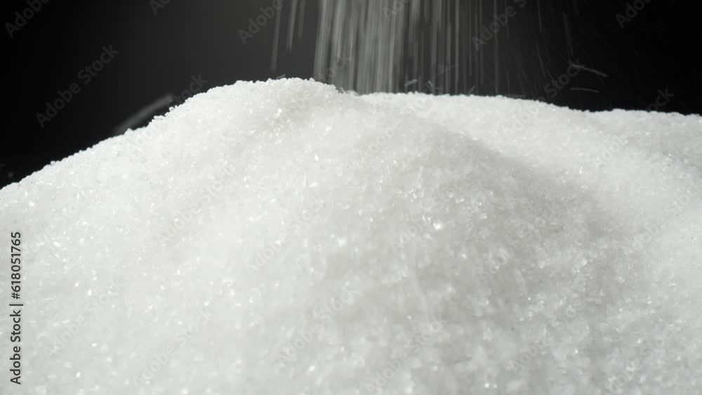 A macro video captures white sugar delicately cascading onto a sleek black background, enchanting viewers with its graceful descent. The probe lens offers a perspective, revealing intricate details
