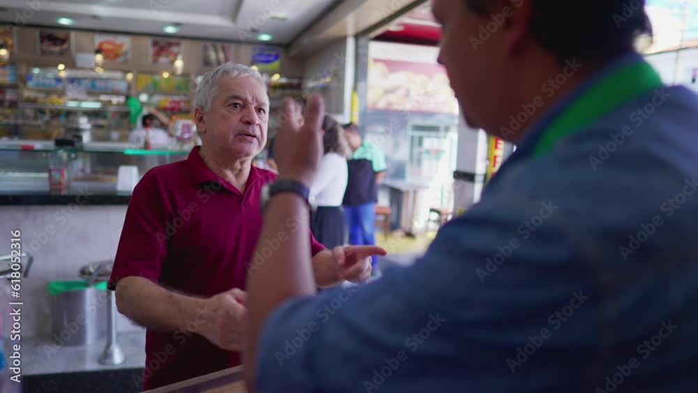 Senior customer interacting with deli cashier at local cafeteria restaurant business. Older person speaking with friend Senior customer interacting with deli cashier at local cafeteria restaurant business. Older person speaking with friend