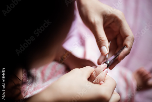 Close-up hand a Mother cuts fingernails of a Baby. Mother uses nail clippers  cuts the baby s nails slowly  while the baby sleeps  In order to cut easily.