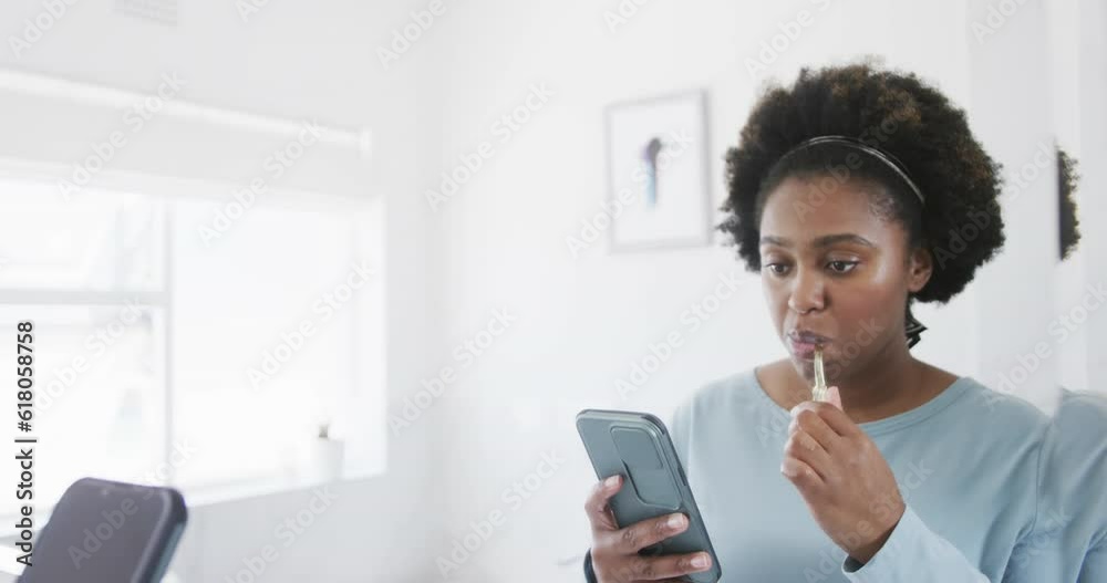 African american woman brushing teeth and using smartphone at bathroom mirror, slow motion African american woman brushing teeth and using smartphone at bathroom mirror, slow motion