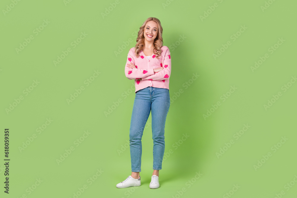 Full body cadre of satisfied young girl wearing trendy pink shirt folded arms confident denim jeans isolated on green color background Full body cadre of satisfied young girl wearing trendy pink shirt folded arms confident denim jeans isolated on green color background