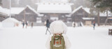Woman tourist Visiting in Sapporo, Traveler in Sweater looking Hokkaido Shrine with Snow in winter season. landmark and popular for attractions in Hokkaido, Japan. Travel and Vacation concept