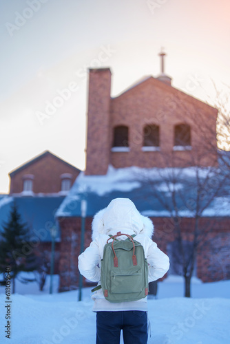 Woman tourist Visiting in Sapporo, Traveler in Sweater looking Sapporo Beer Museum with Snow in winter season. landmark and popular for attractions in Hokkaido, Japan. Travel and Vacation concept photo