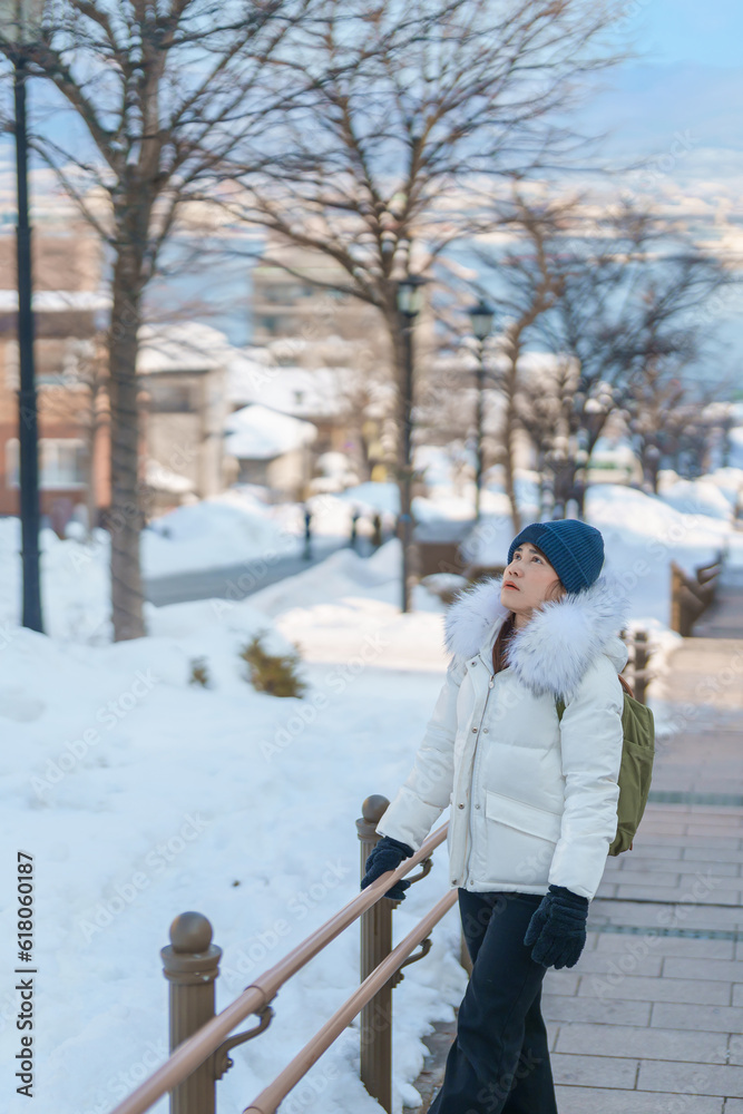 Woman tourist Visiting in Hakodate, Traveler in Sweater sightseeing Hachiman Zaka Slope with Snow in winter. landmark and popular for attractions in Hokkaido, Japan. Travel and Vacation concept Woman tourist Visiting in Hakodate, Traveler in Sweater sightseeing Hachiman Zaka Slope with Snow in winter. landmark and popular for attractions in Hokkaido, Japan. Travel and Vacation concept