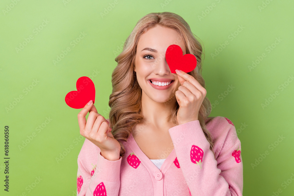 Photo of optimistic cheerful lovely cute girl dressed pink cardigan paper heart postcard cover eye isolated on green color background Photo of optimistic cheerful lovely cute girl dressed pink cardigan paper heart postcard cover eye isolated on green color background