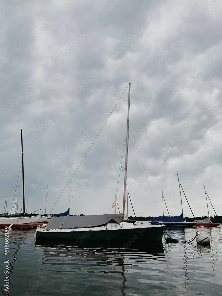 a group of boats floating on top of a lake under cloudy skies