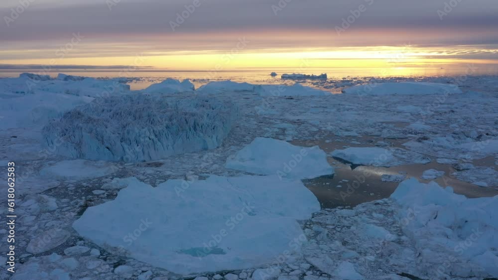 Aerial of the big glaciers in the sea with the golden sunset shining in the background Aerial of the big glaciers in the sea with the golden sunset shining in the background
