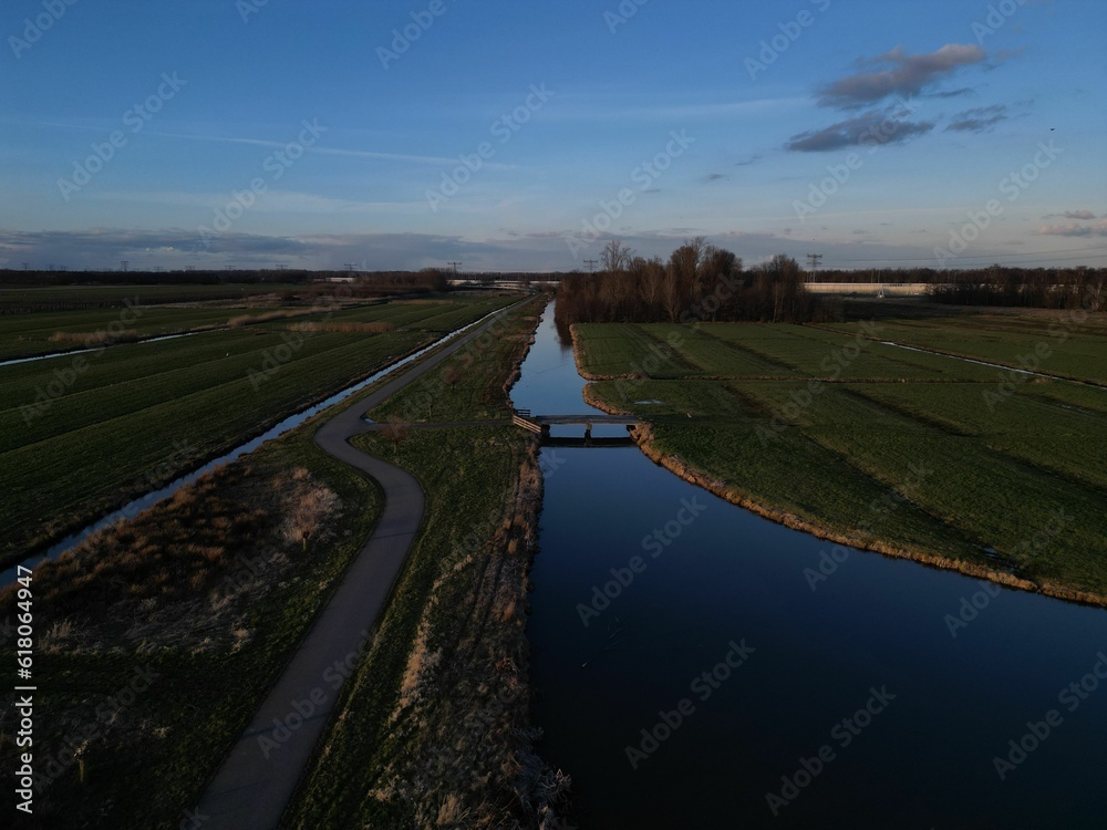 Is an aerial shot of a small river flowing through a sprawling green field