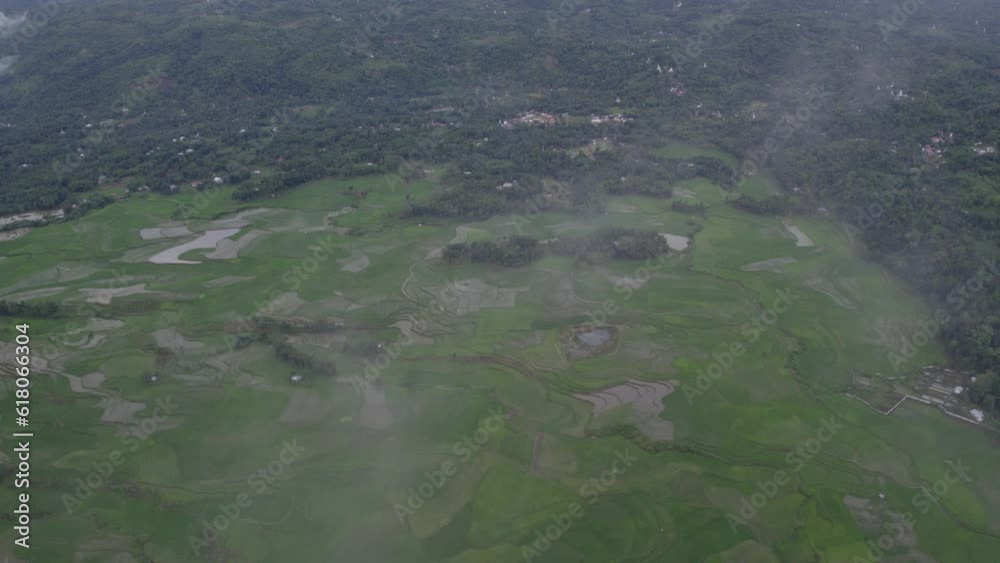 Wide shot of lush green rice paddies with low clouds at Sumba island, aerial Wide shot of lush green rice paddies with low clouds at Sumba island, aerial