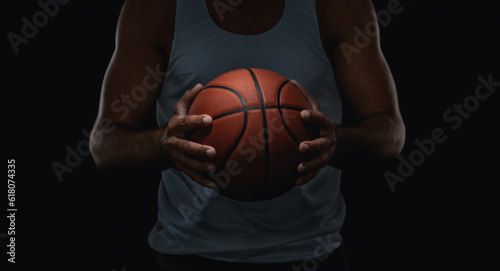 Close up of basketball ball in athlete hands, isolated on black background with copy space