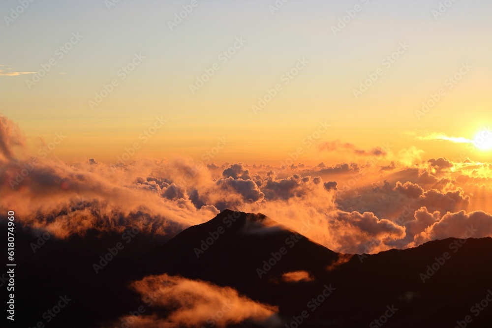 Aerial view of the majestic mountain covered in fluffy clouds at sunset