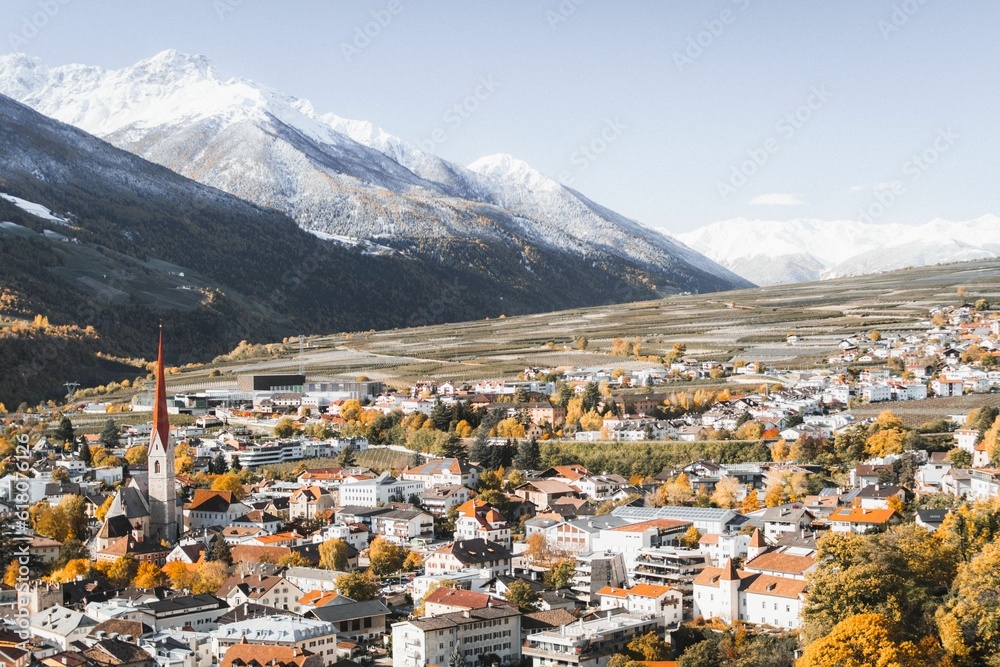 Aerial view of a small town in autumn foliage on the background of beautiful snowy mountains